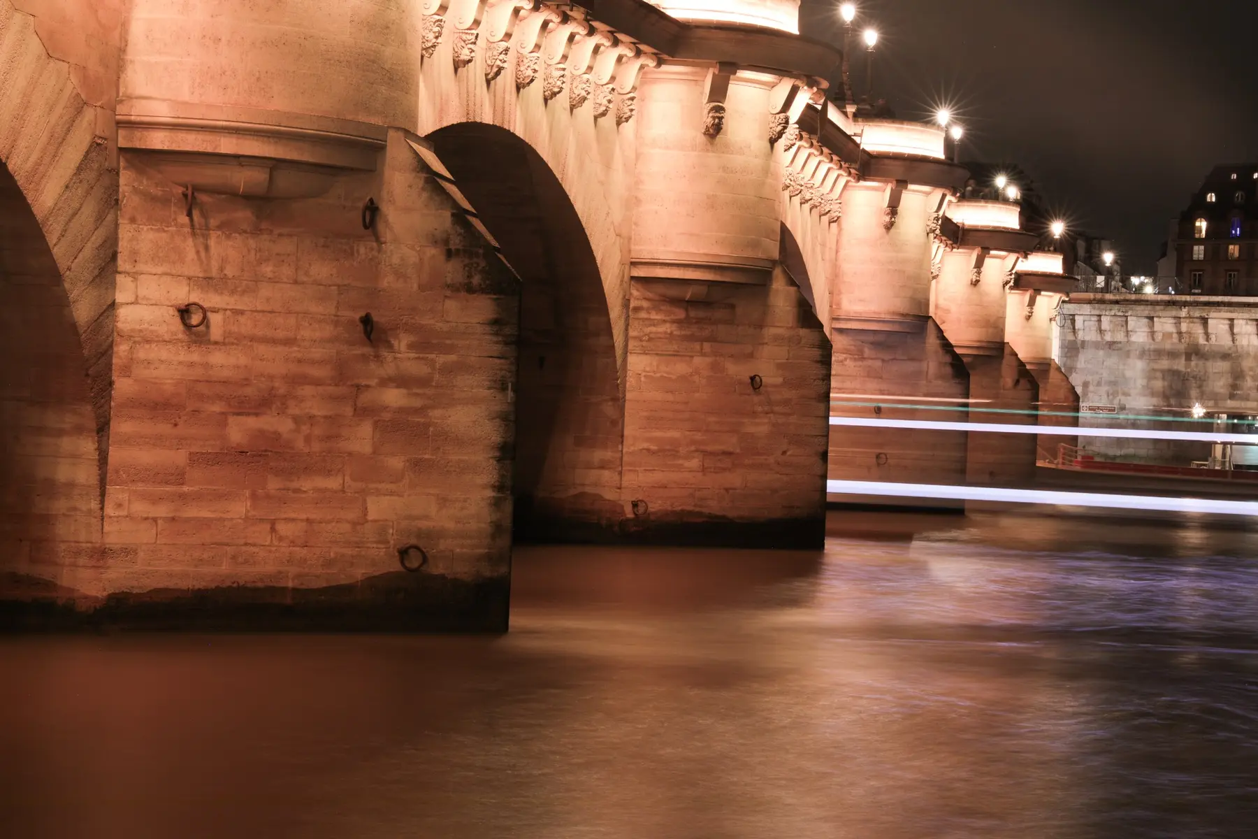 Long-exposure night photograph of an illuminated stone bridge over a river